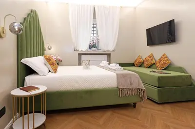 a bedroom with a bed and two green chairs at Vatican Loft - Liberty Collection in Rome