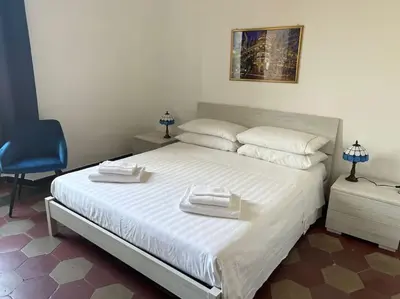 a bedroom with a large white bed with a blue chair at Domus Alexandra in Rome