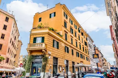 a tall yellow building with a balcony on a street at San Lorenzo Style Apartment in Rome