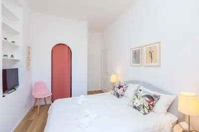 a white bedroom with a bed and a tv at San Lorenzo Style Apartment in Rome