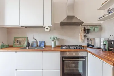 a kitchen with white cabinets and a stove top oven at Roma is amoR in Rome