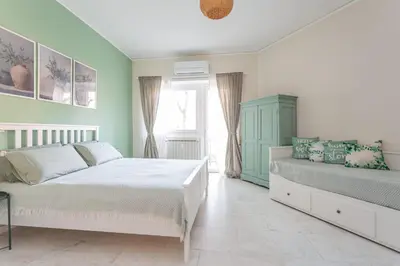 a bedroom with a bed and a couch and a window at Roma is amoR in Rome