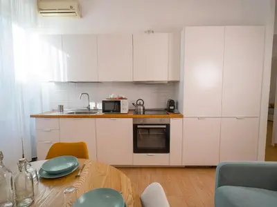 a small kitchen with white cabinets and a table at 2BDR Testaccio Sweet Home in Rome