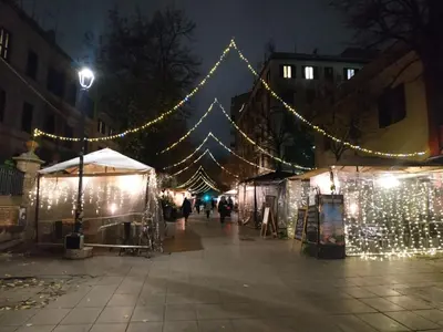 a street with christmas lights and people walking past tents at DàLù alPigneto in Rome