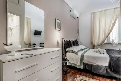 a white bedroom with a bed and a mirror at Villa Borghese Gallery Rooms in Rome