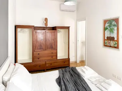 a white bedroom with a wooden dresser and a couch at The Twenty - Vatican Apartment in Rome