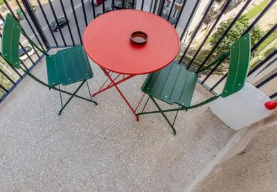 a red table and two green chairs next to a fence at Your Whole Suite in Rome