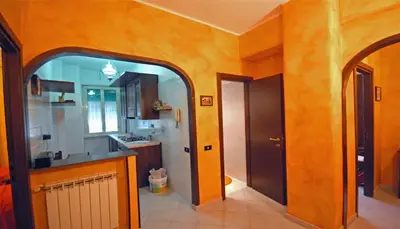 a kitchen with orange walls and an arched doorway at Ababaluba - Colosseo - San Giovanni in Rome