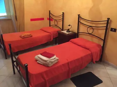 three beds in a room with red sheets at Ababaluba - Colosseo - San Giovanni in Rome