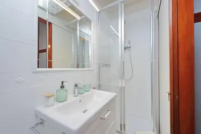 a white bathroom with a sink and a shower at La Petite Urbana Apartment in Rome