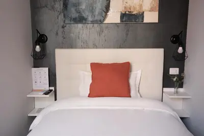 a bedroom with a white bed with a orange pillow at Numi B&B in Rome