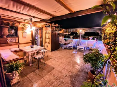 an outdoor patio with a table and chairs at night at Domus Corneliæ - Romantico Attico Roman & Jacuzzi - Metro A Cornelia in Rome