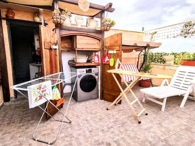 a kitchen with a washing machine and chairs on a patio at Domus Corneliæ - Romantico Attico Roman & Jacuzzi - Metro A Cornelia in Rome