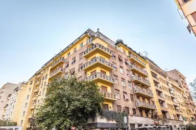 a tall yellow building with a tree in front of it at Sapienza Apt - Modern House in Piazza Bologna in Rome