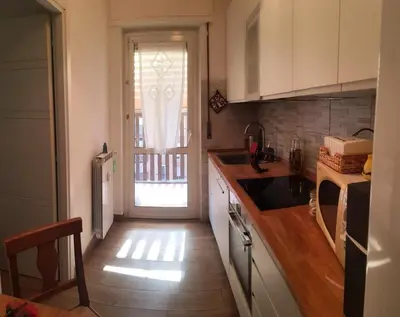 a kitchen with white cabinets and a door to a yard at AugustoVera19 Tourist Accommodation in Rome
