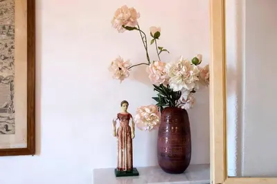 a vase with pink flowers and a statue on a shelf at Colosseo The Family Home in Monti in Rome