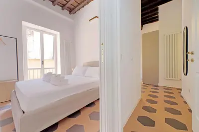 a white bedroom with a bed and a window at Trastevere Cisterna 4 in Rome