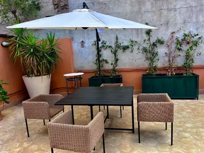 a black table and chairs with an umbrella and potted plants at Trastevere Cisterna 4 in Rome