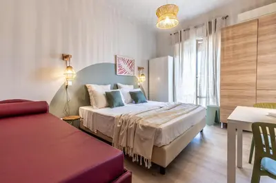 a bedroom with a bed and a table and a couch at Dafne Rooms un soggiorno energico e pieno di vita in Rome