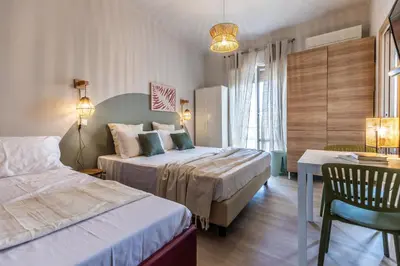 a hotel room with two beds and a table and chairs at Dafne Rooms un soggiorno energico e pieno di vita in Rome