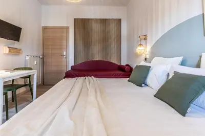 a bedroom with a large white bed with a red couch at Dafne Rooms un soggiorno energico e pieno di vita in Rome