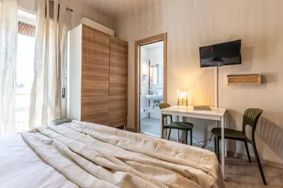 a bedroom with a bed and a table and a desk at Dafne Rooms un soggiorno energico e pieno di vita in Rome