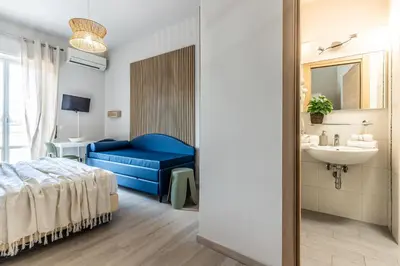 a bedroom with a bed and a sink and a blue couch at Dafne Rooms a relaxing piece of paradise in Rome