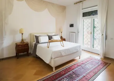 a bedroom with a white bed and a red rug at Villa Mara Appia antica in Rome