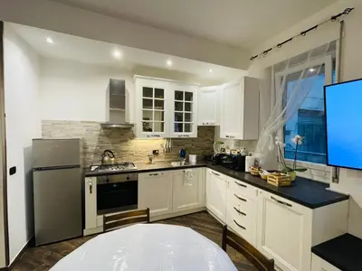 a kitchen with white cabinets and a large screen tv at roominrome Alexander Apartment in Rome