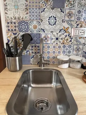 a stainless steel sink in a kitchen with blue and white tiles at Angolo dè Trastevere - Accogliente e silenzioso in Rome