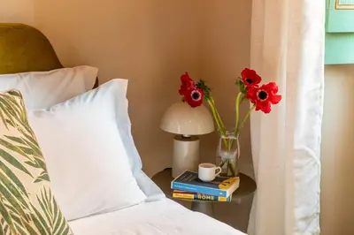a vase of flowers on a table next to a bed at ROMAC Baullari III - Family apartment in Campo de Fiori in Rome