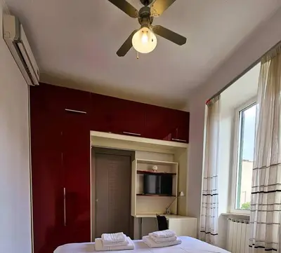 a bedroom with red cabinets and a ceiling fan at Appartamento vista Colosseo in Rome