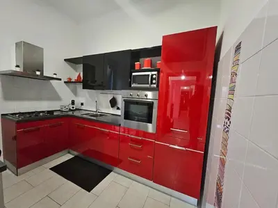 a kitchen with red cabinets and a microwave at Appartamento vista Colosseo in Rome