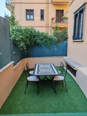 a table and chairs on a patio with grass at San Pietro Green Home in Rome