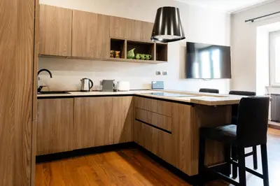 a kitchen with wooden cabinets and a black chair at Caffarella Suite in Rome