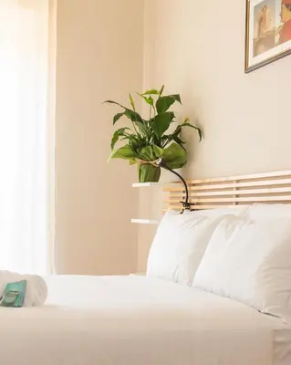 a bedroom with a white bed with a potted plant at Porta Pia apartment ZENO 53 in Rome