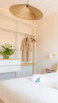 a bedroom with a white bed with a dresser and a coat at Porta Pia apartment ZENO 53 in Rome