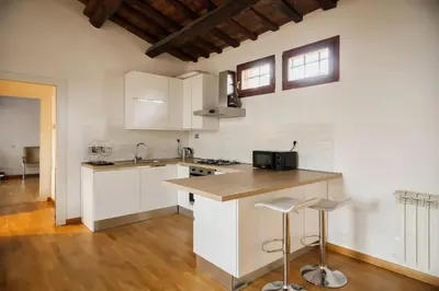 a kitchen with white cabinets and a counter with stools at HC - Palazzo Altieri Exclusive Penthouses in Rome