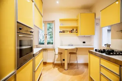 a kitchen with yellow cabinets and a table with chairs at HC - Live Roma Pantheon View in Rome