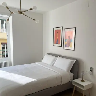 a white bedroom with a bed and two pictures on the wall at Simposio - Luxury Apartment Rome in Rome
