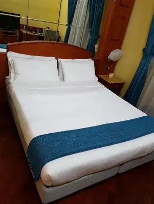 a large white bed with a blue blanket on it at 69 Manin Termini in Rome
