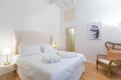 a white bedroom with a white bed and a chair at Appartamento a Piazza di Spagna in Rome