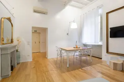 a white living room with a table and a mirror at Appartamento a Piazza di Spagna in Rome