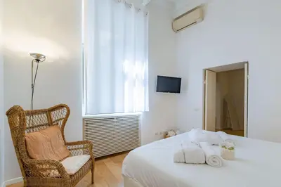 a bedroom with a bed and a chair and a window at Appartamento a Piazza di Spagna in Rome