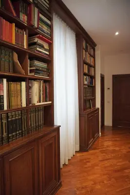 a library with wooden shelves filled with books at Holidays Palumbo in Rome