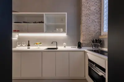 a kitchen with white cabinets and a brick wall at Spagna Suite Luxury Home - Trevi Fountain in Rome
