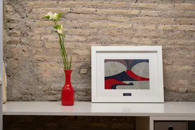 a red vase with a flower in it next to a picture at Spagna Suite Luxury Home - Trevi Fountain in Rome