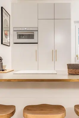 a kitchen with white cabinets and a counter with two stools at Silent 2 Bdrm heart of Trastevere in Rome