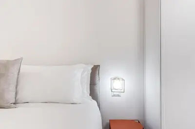 a bed with white sheets and a light on a wall at Silent 2 Bdrm heart of Trastevere in Rome