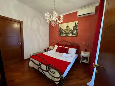 a bedroom with a bed with red walls and a chandelier at Doria Boutique Apartment in Rome